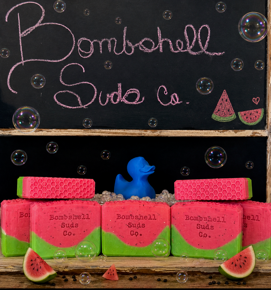 Bar soaps with watermelon design and 'Bombshell Suds Co.' branding, displayed against a chalkboard background.