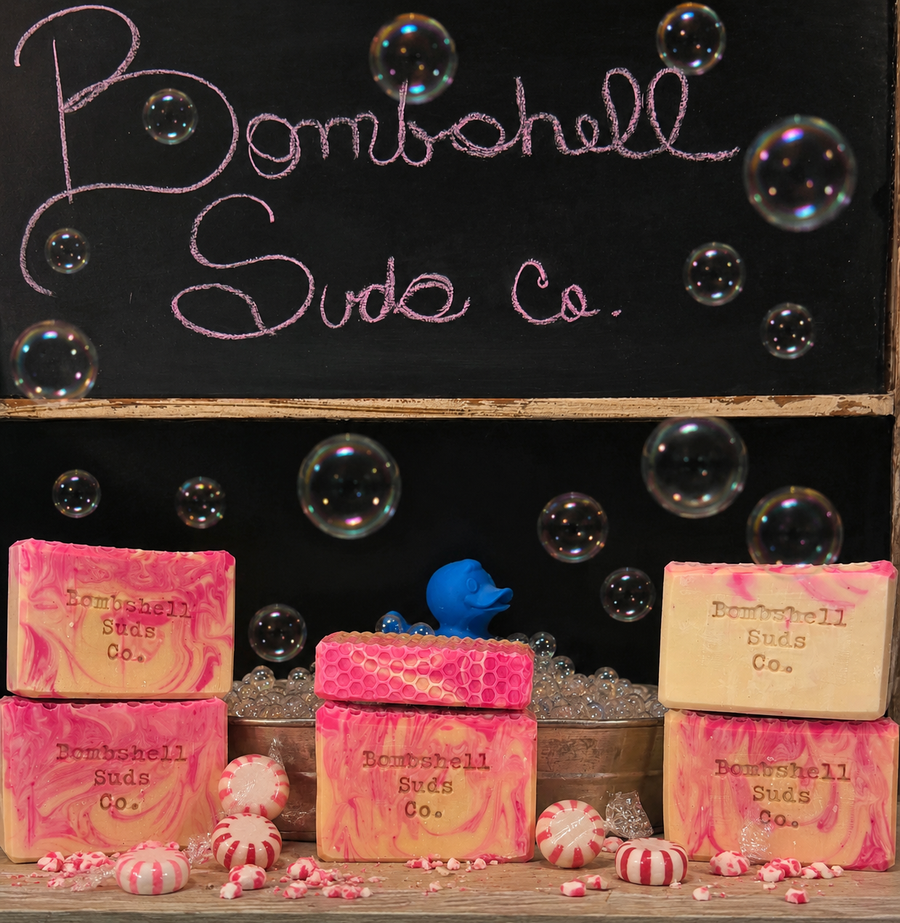 Bombshell Suds Co. soaps with decorative elements on a black background with bubbles.
